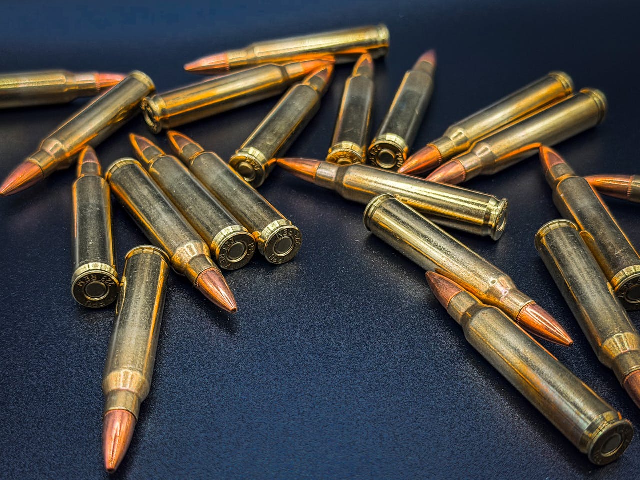 A detailed close-up of scattered rifle bullets on a dark surface, showcasing ammunition details.