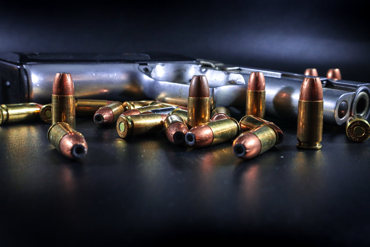 A detailed view of ammunition and a handgun with scattered bullets on a dark background.